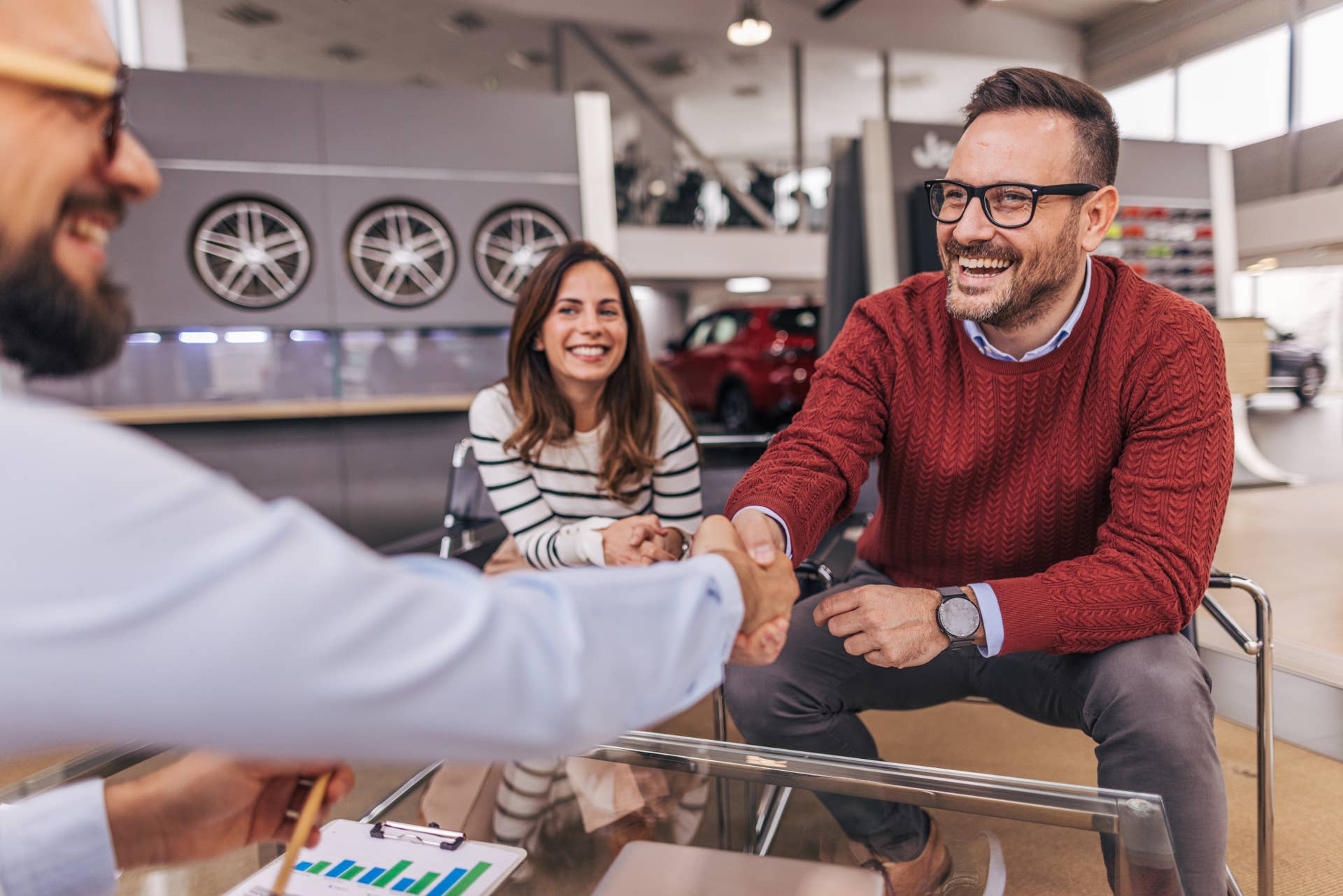 An auto salesperson shakes the hand of a man buying a car