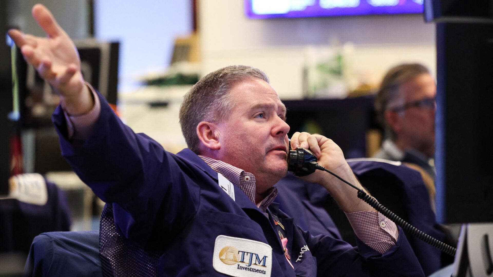 A NYSE trader on the floor of the exchange on a phone.