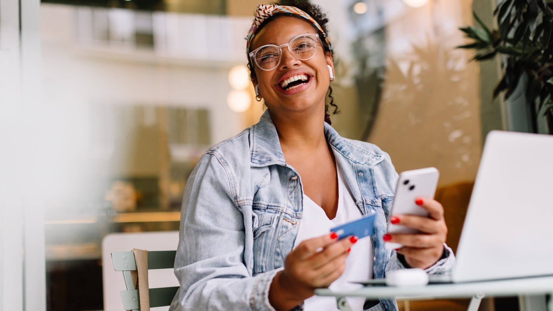 A woman holding a phone and a credit card is shopping online.