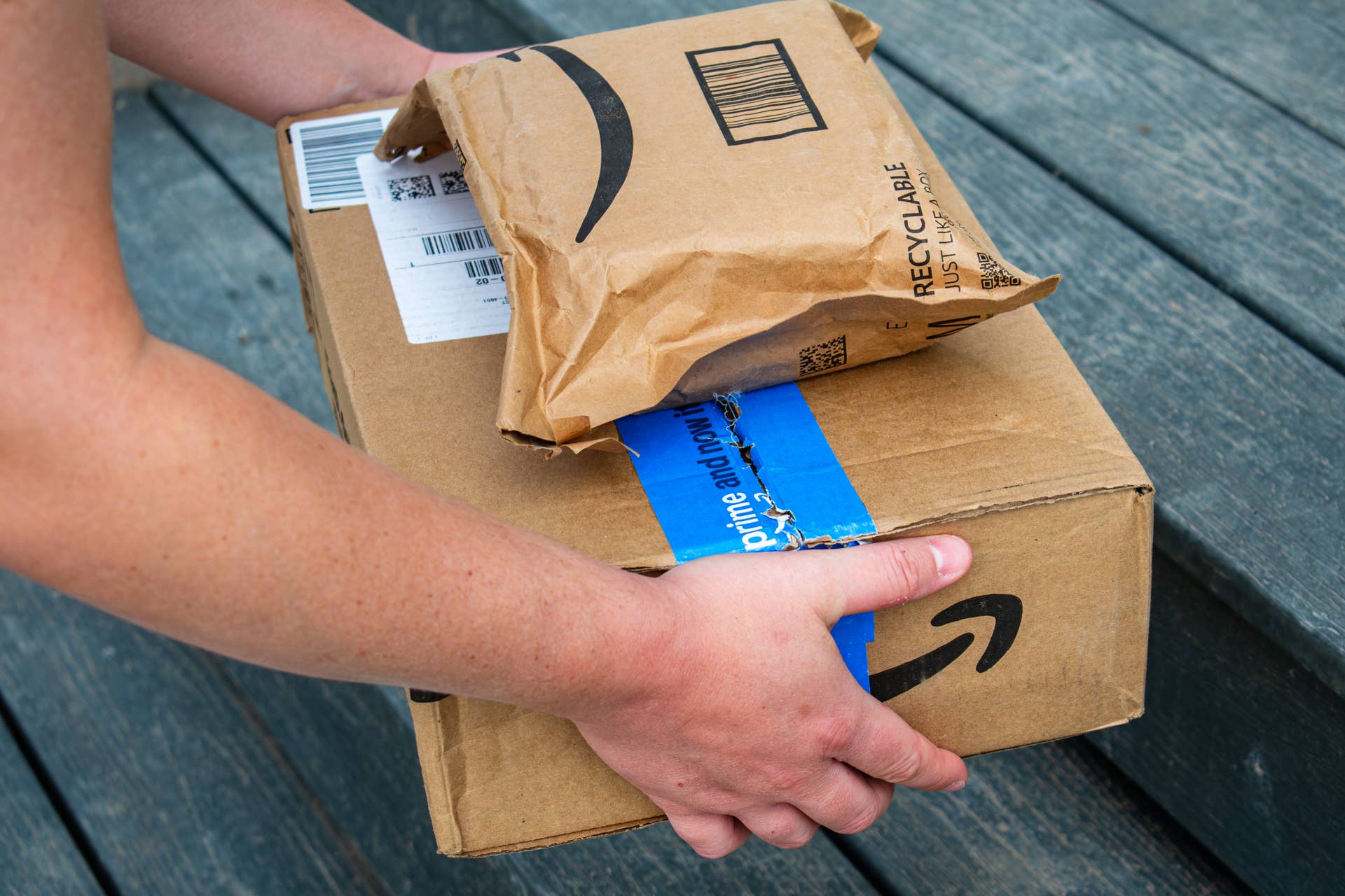 An Amazon worker holding a stack of packages.