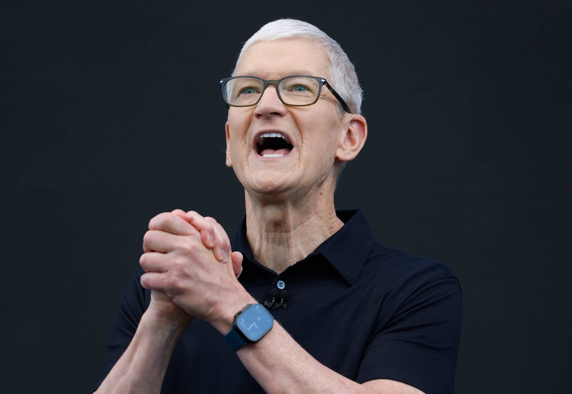 Apple CEO Tim Cook is speaking during an event, standing in front of a black screen.
