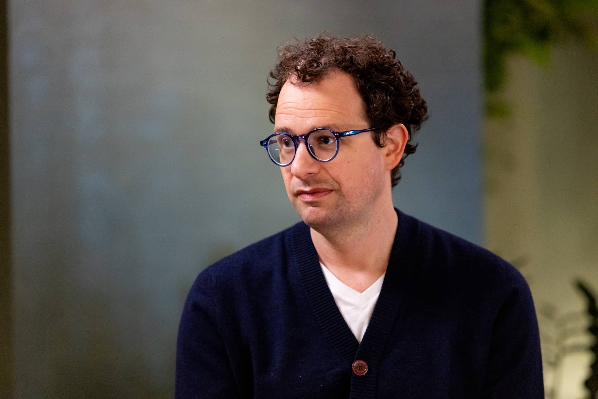 Anthropic co-founder and CEO Dario Amodei sits indoors wearing glasses.