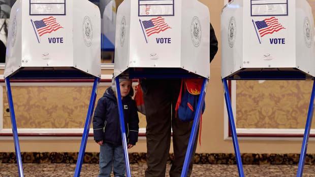 A voter takes a small child to the polls Tuesday as Americans across the country choose House members, senators, governors and more.
