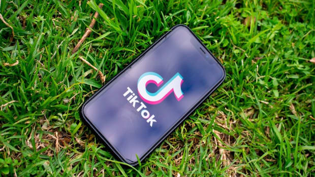 Smartphone laying on grass, TikTok app on screen