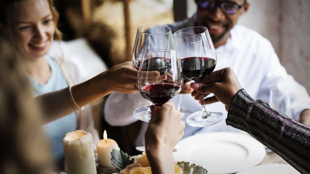 Restaurant patrons give a toast with their wine glasses in a restaurant. Lead.