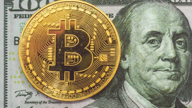 Image of physical Bitcoin against US 100 dollar bill.