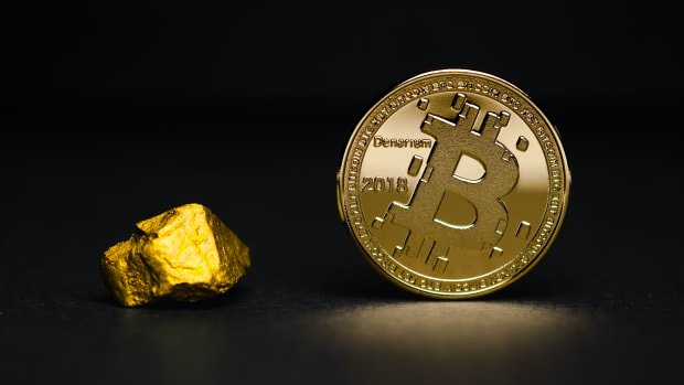 Lump of gold and a golden physical Bitcoin next to each other.