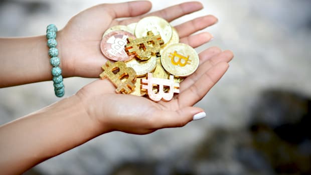 Female hands holding Bitcoin against waterfall background.