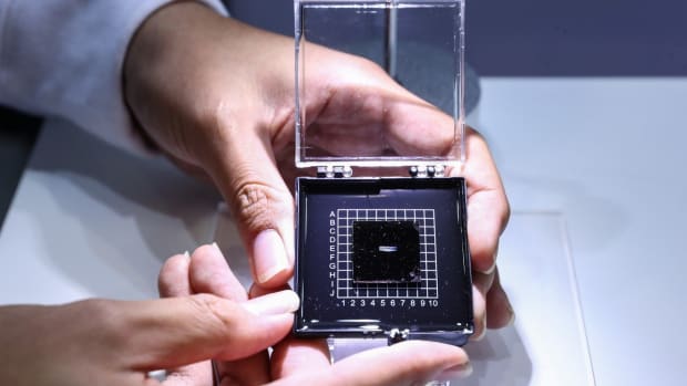A staff member shows a photonic AI chip during a press preview of the 2018 National Mass Innovation and Entrepreneurship Week in Beijing. Photo: Xinhua
