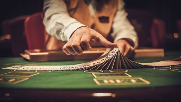 A dealer shuffles a deck of cards at a casino game. Casino Gambling Lead