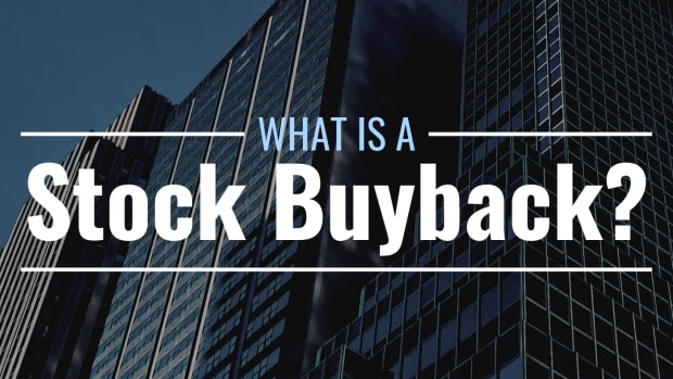 Darkened photo of tall office buildings with text overlay that reads "What Is a Stock Buyback?"