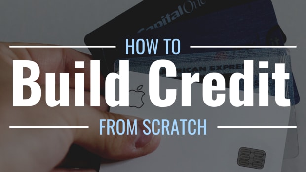 Darkened photo of a hand holding four credit cards with text overlay that reads "How to Build Credit From Scratch"