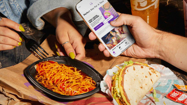 People eat at Taco Bell while one looks at a menu on their phone. lead.