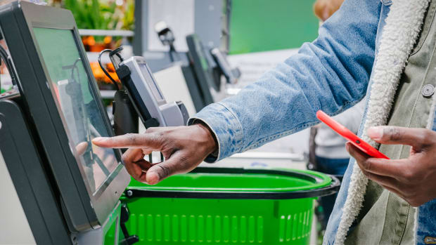 A person uses a self-checkout kiosk. Grocery Checkout Lead JS 102022