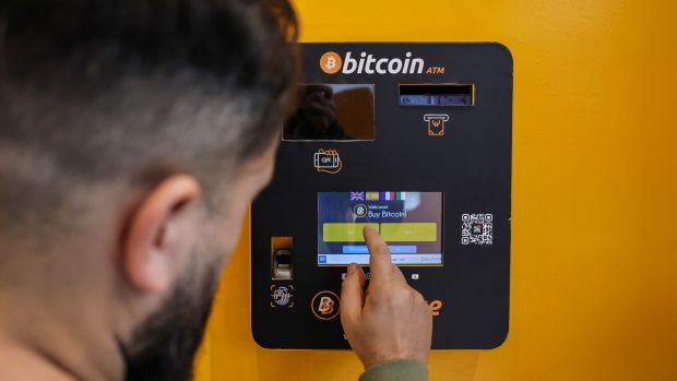 A worker uses a Bitcoin automated teller machine (ATM) inside a BitBase cryptocurrency exchange in Barcelona, Spain, on Tuesday, Dec. 5, 2023. Bitcoin shrugged off a slide in global markets during a rally to a more than 19-month high, a sign of its decoupling from other assets. Photographer: Angel Garcia/Bloomberg via Getty Images