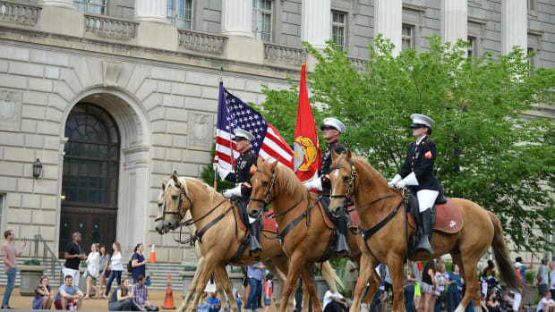 Three men on horses hold flags during a Memorial Day Parade