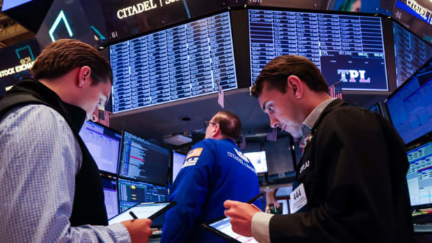 People standing under screens on the floor of the New York Stock Exchange. lead.