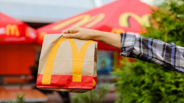 At a McDonald's fast-food restaurant, a man holds a paper bag. lead.