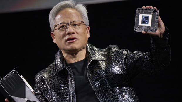Jensen Huang, CEO of Nvidia, holds the company's new GeForce RTX 50 series graphics cards and a Thor Blackwell robotics processor.