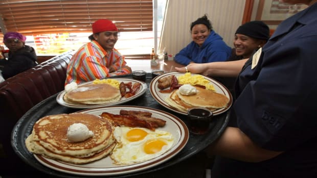 A Denny's server delivers Grand Slam breakfasts to seated customers. lead.