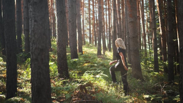 A woman walks through a Japanese forest. lead.
