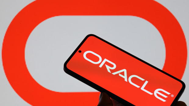The Oracle logo is displayed on a mobile phone with the company's branding seen in the background.