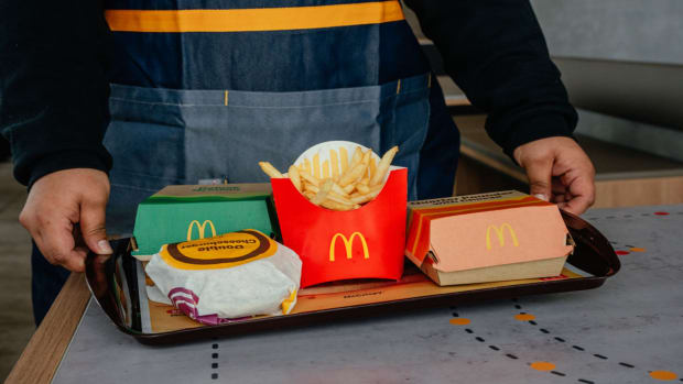 An employee carries a tray of food, including fries and hamburgers, to a customer at a McDonald's restaurant.