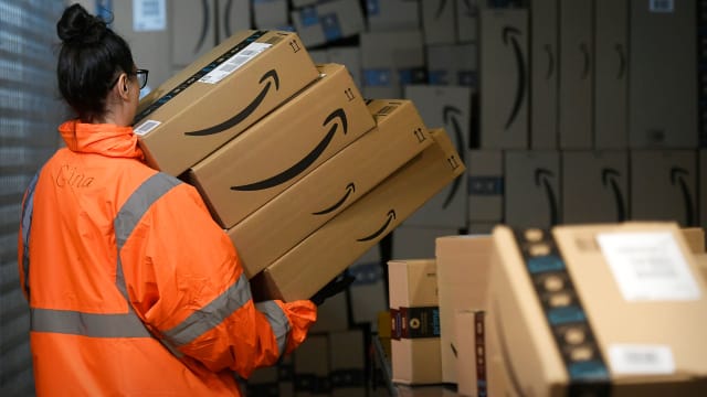 An Amazon worker carries packages. Lead.