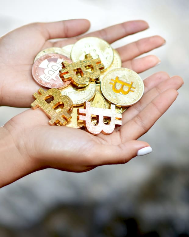 Female hands holding Bitcoin against waterfall background.