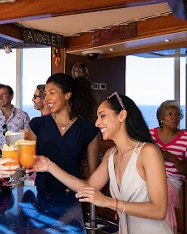 People have a drink in a Carnival Cruise Bar Lead JS