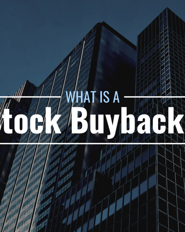 Darkened photo of tall office buildings with text overlay that reads "What Is a Stock Buyback?"