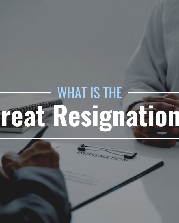 Darkened photo of an employee signing their resignation letter across a desk from a boss/manager with text overlay that reads "What Is the Great Resignation?" chayanuphol
