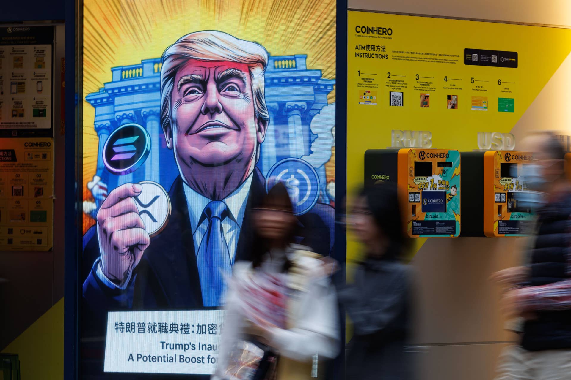 People walk past an advertisement feature Donald Trump with Solana, XRP, USDC Bitcoin in Hong Kong.