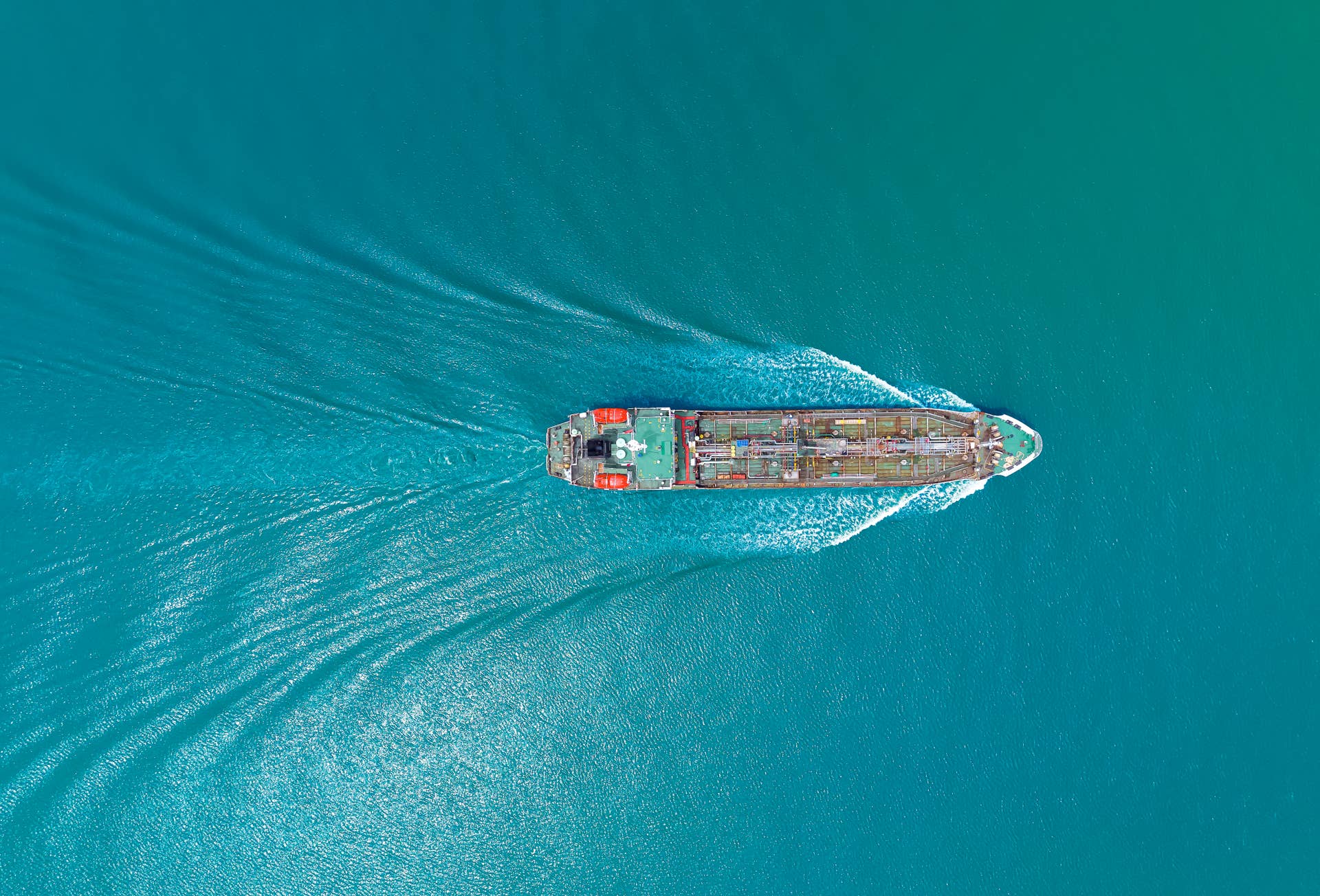Aerial top view, Green Oil tankers, orange lifeboats at the bow are running at high speed and beautiful waves in the sea. 