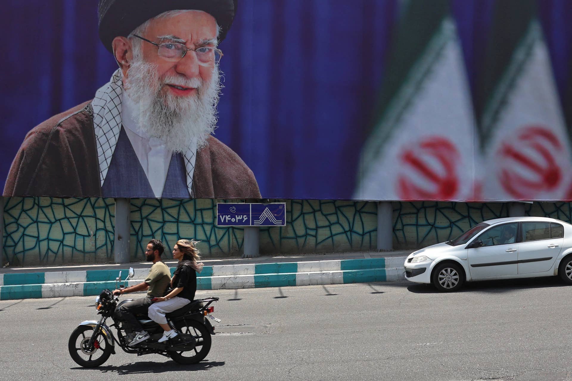 motorists ride past a giant billboard bearing a picture of irans late supreme leader ayatollah ali khamenei ahead of his funeral in tehran on july 2 2026