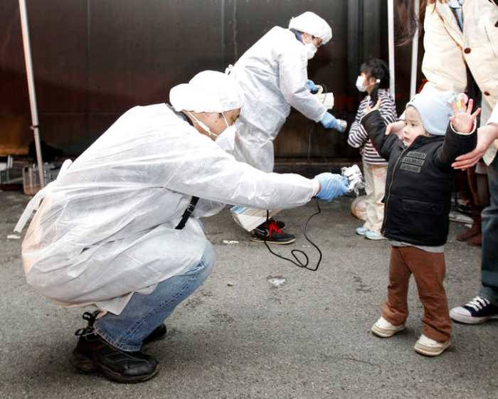 Officials in protective gear check for signs of radiation on children who are from the evacuation area near the Fukushima Daini nuclear plant in Koriyama in this March 13, 2011 photo. Reuters/Kim Kyung-Hoon/Files