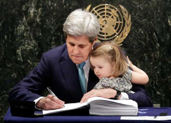 Then-Secretary of State John Kerry held his granddaughter as he signed the Paris climate agreement in 2016. AP Photo/Mark Lennihan