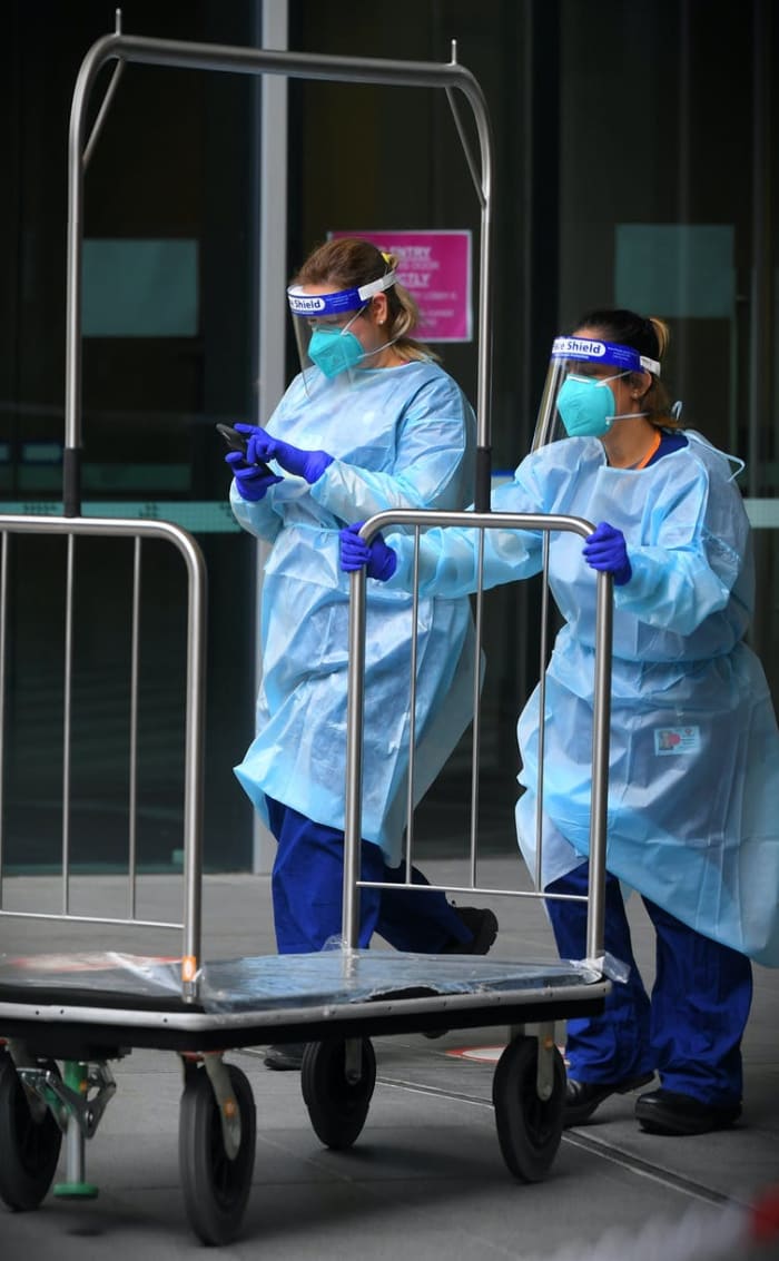 Healthcare workers with luggage trolley outside Novotel South Warf Melbourne, December 7. JAMES ROSS/AAP