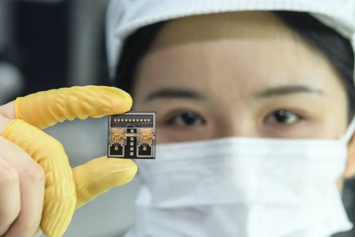A worker in a Chinese research laboratory holds a chip used in automobile radar systems. Liu Yucai/Visual China Group via Getty Images