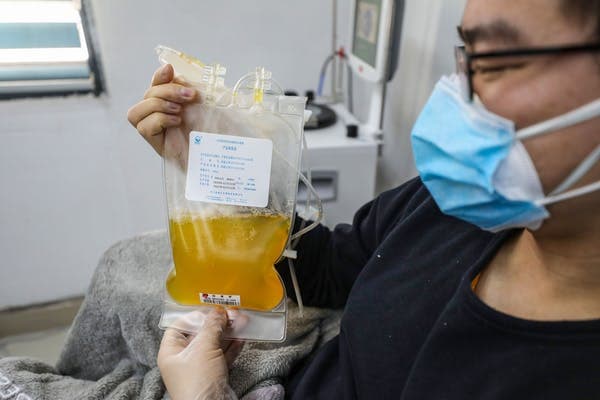 A doctor who has recovered from COVID-19 holds up a bag of his own donated plasma in Wuhan, China. STR/AFP via Getty Images