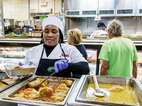 Blacks are more likely to work in low-paying jobs, such as custodial work and food service, that cannot be done remotely. Here, a server adds stuffed cabbage to an order at The Boys Farmers Market in Delray Beach, Fla. Jeffrey Greenberg/Universal Images Group via Getty Images