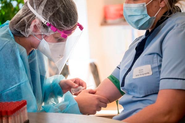 A nurse has blood drawn to check whether she has antibodies to SARS-CoV-2, and hopefully immunity. SEBASTIEN BOZON/AFP via Getty Images