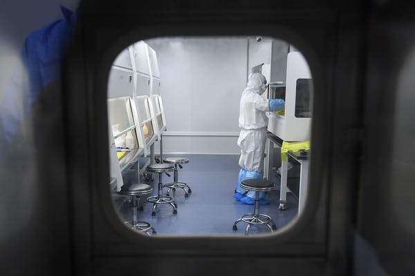In early February, a laboratory technician works on virus samples from patients sick in Wuhan, China. STR/AFP via Getty Images