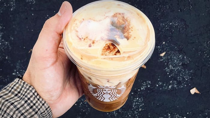 A man holds an ice cold Starbucks coffee.  Starbucks Pumpkin Spice Latte Lead