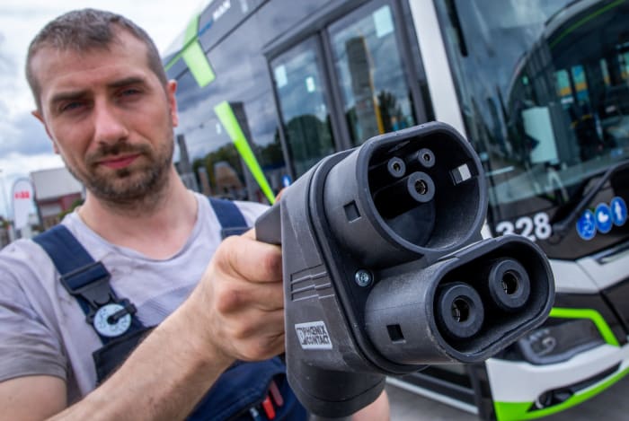 02 August 2023, Mecklenburg-Western Pomerania, Rostock: Sebastian Schuh holds a charging plug for charging an electric bus at the new depot of Rostocker Straßenbahn AG (RSAG). After six months of conversion work, the site for regular service buses has been adapted for alternative drive systems. The buses can be fueled with electric energy and biomethane, and the plan is to gradually convert all bus services to climate-friendly drive systems over the next few years. Photo: Jens Büttner/dpa (Photo by Jens Büttner/picture alliance via Getty Images)
