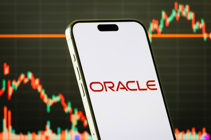 A smartphone shows the logo of Oracle Corporation.
