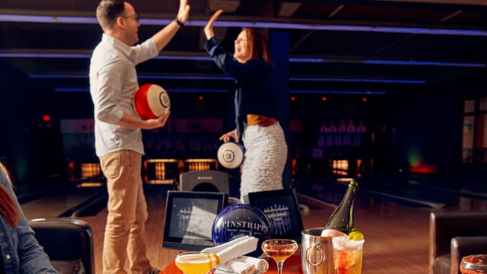 People are bowling at Pinstripes, a family entertainment restaurant.