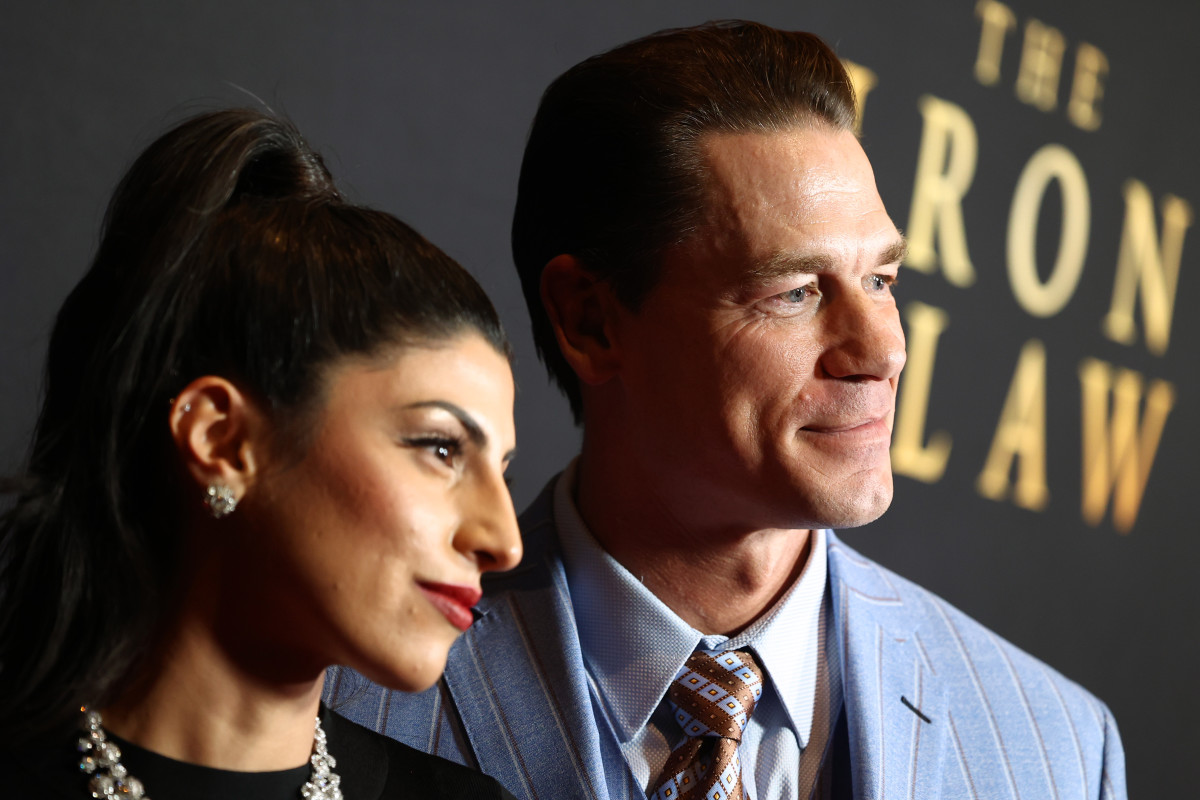 Shay Shariatzadeh and John Cena from the neck up posing for photos on the red carpet of "The Iron Claw" premiere.