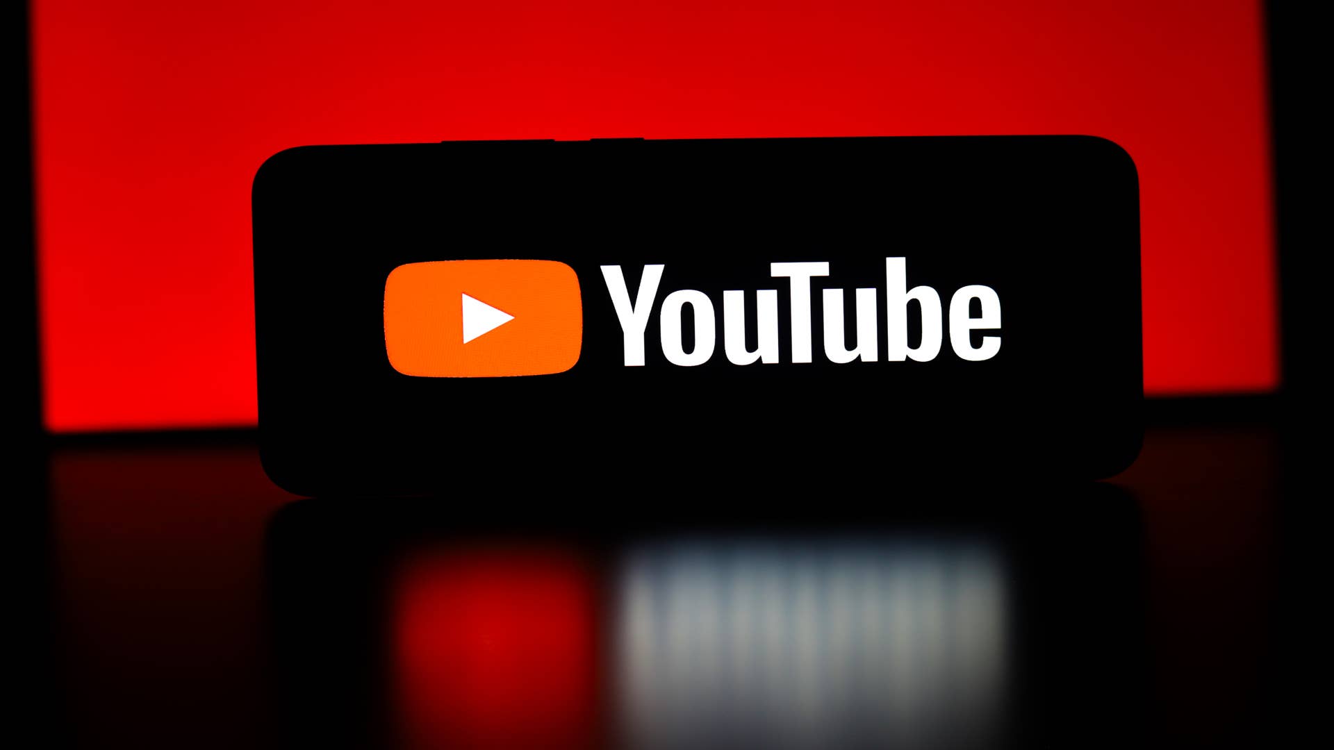 The YouTube logo appears on a smartphone screen