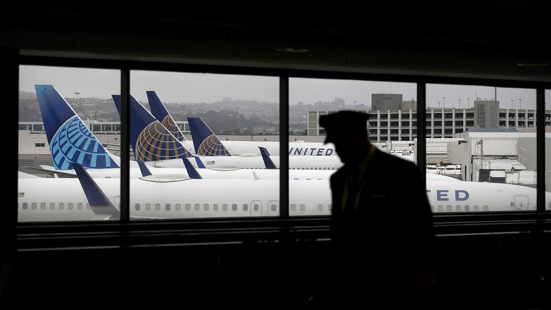 A man looks out the window at an airport at United Airlines planes. Lead JS 011823
